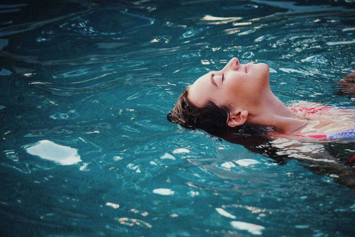 Una donna galleggia rilassata in piscina con gli occhi chiusi