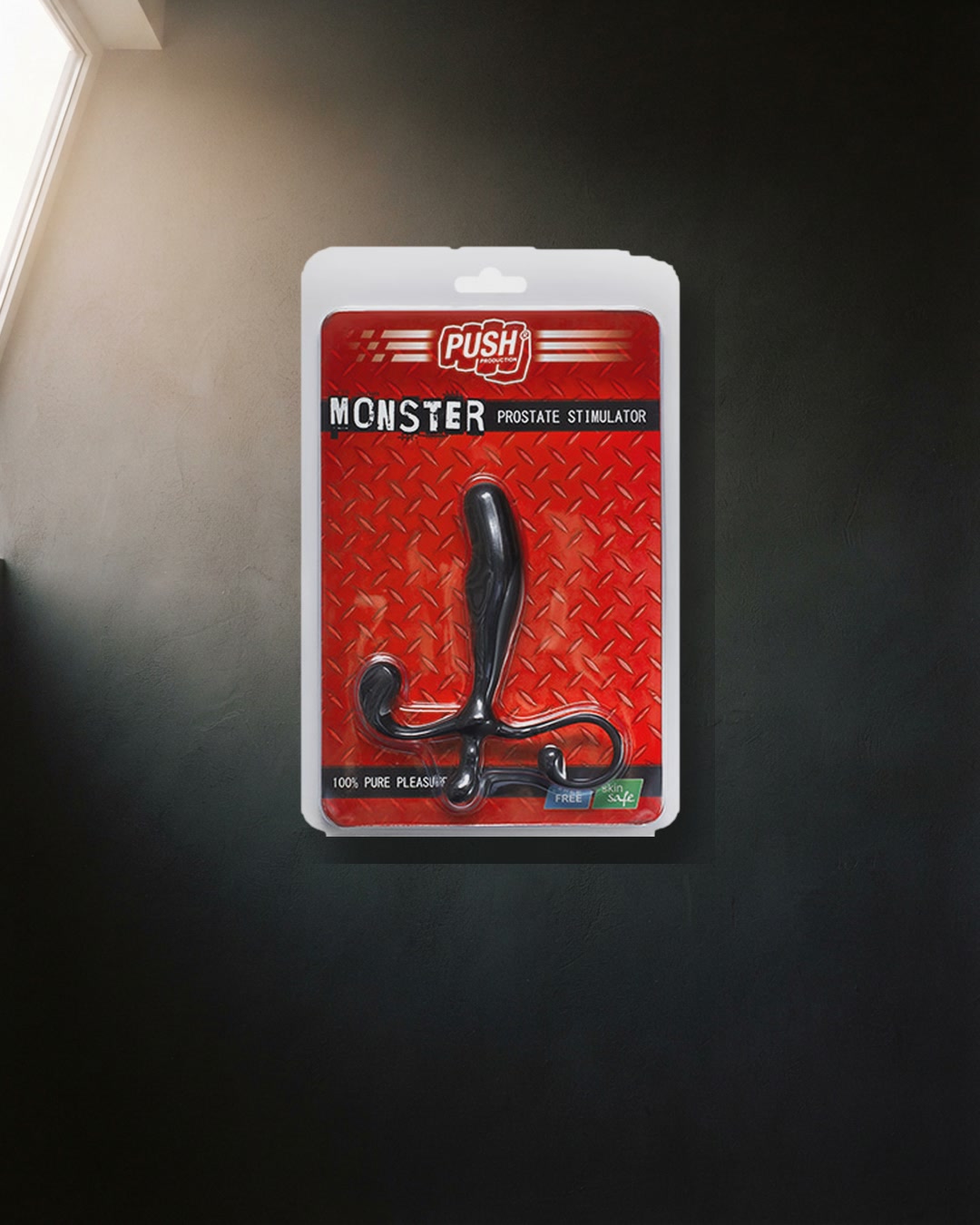 Push Monster, stimolatore prostatico nel blister rosso appeso a una parete scura